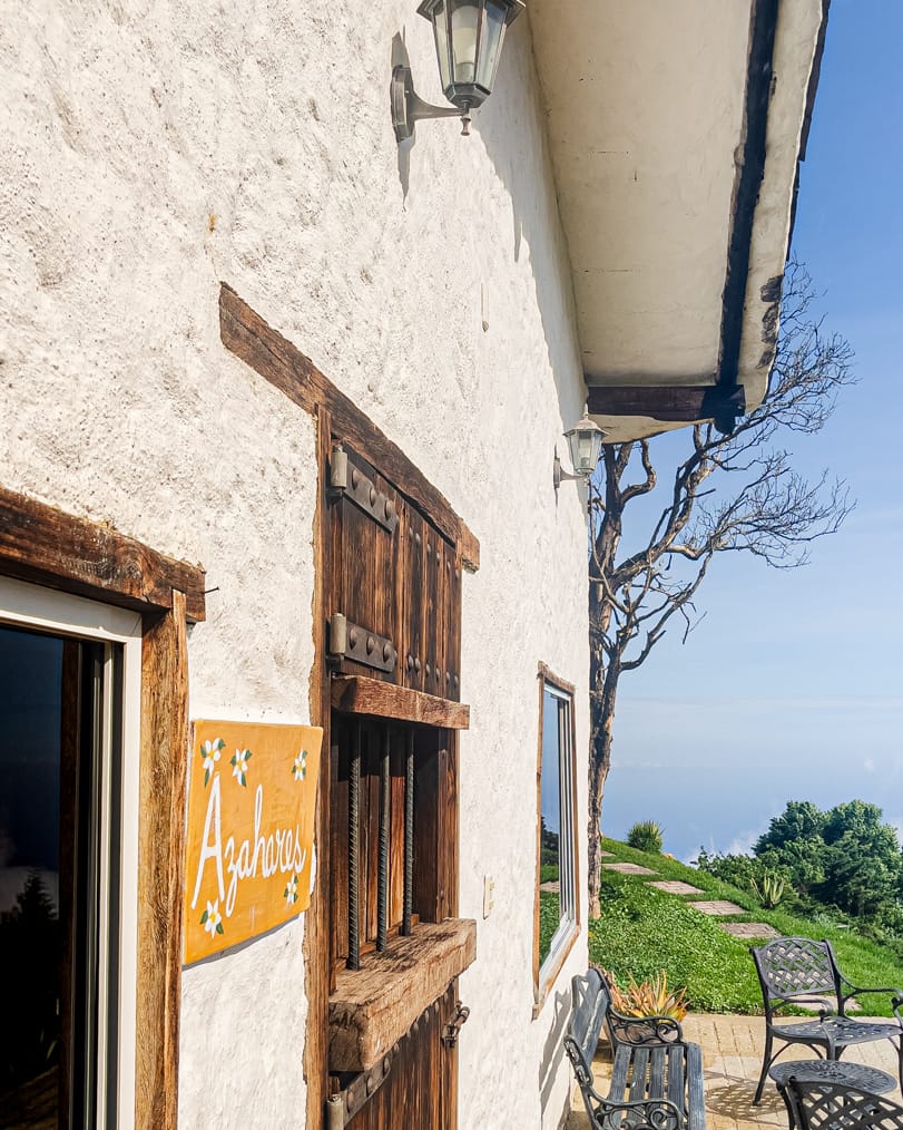 El letrero pintado de Azahares junto a la ventana de madera, con el mar Caribe al fondo del jardín