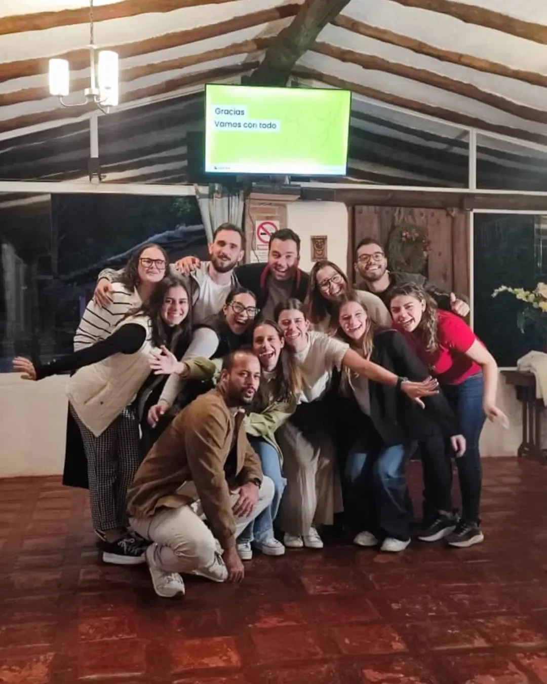 Grupo de participantes posa sonriendo al final de un taller en el salón de vigas de madera de Posada Tarahumara.