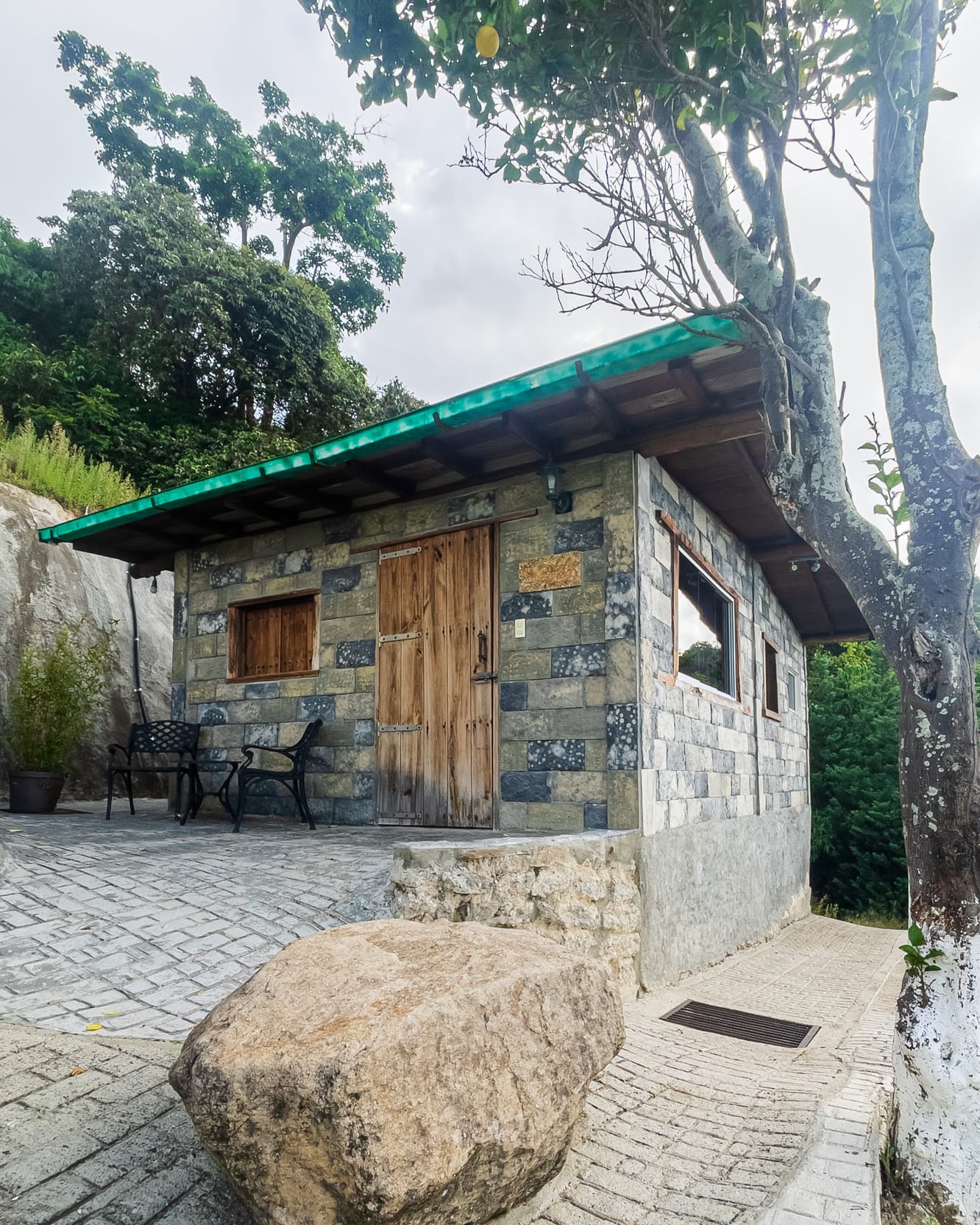 Bloques de piedra y puerta de madera de la Escondida, con sillas de hierro en el patio adoquinado