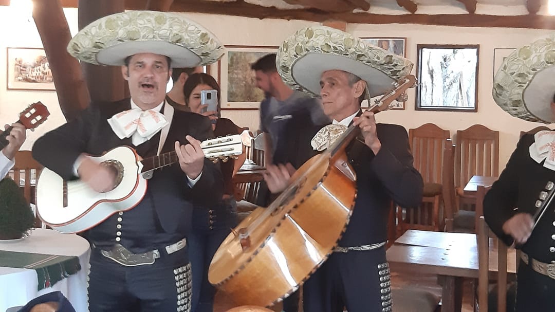 Mariachis con sombreros bordados tocan guitarra y guitarrón entre las mesas del Restaurante Tarahumara, Galipán.