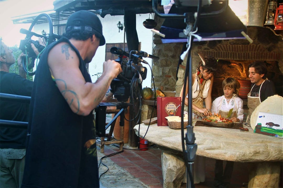 Camarógrafo graba a una cocinera y dos niños junto al horno de piedra durante un rodaje en Posada Tarahumara.
