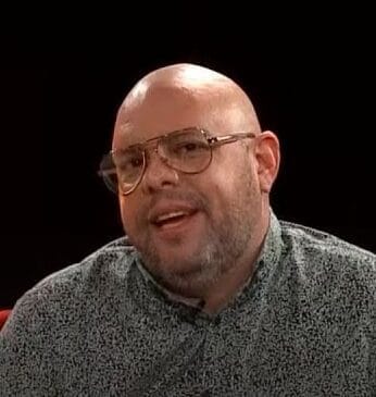 José A. Sánchez, Coco de Radio Rochela, con lentes y camisa estampada en un set de televisión; recomienda Tarahumara