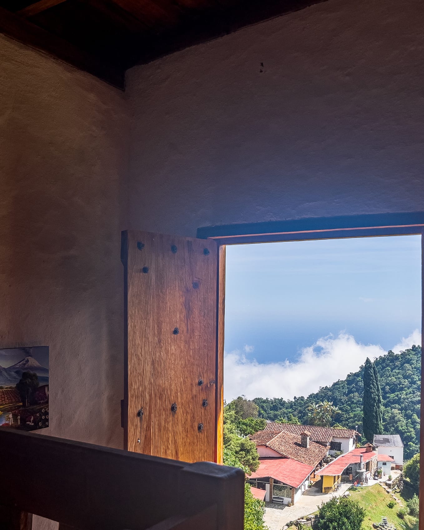 Puerta abierta hacia los techos rojos de Galipán con las nubes trepando desde la costa
