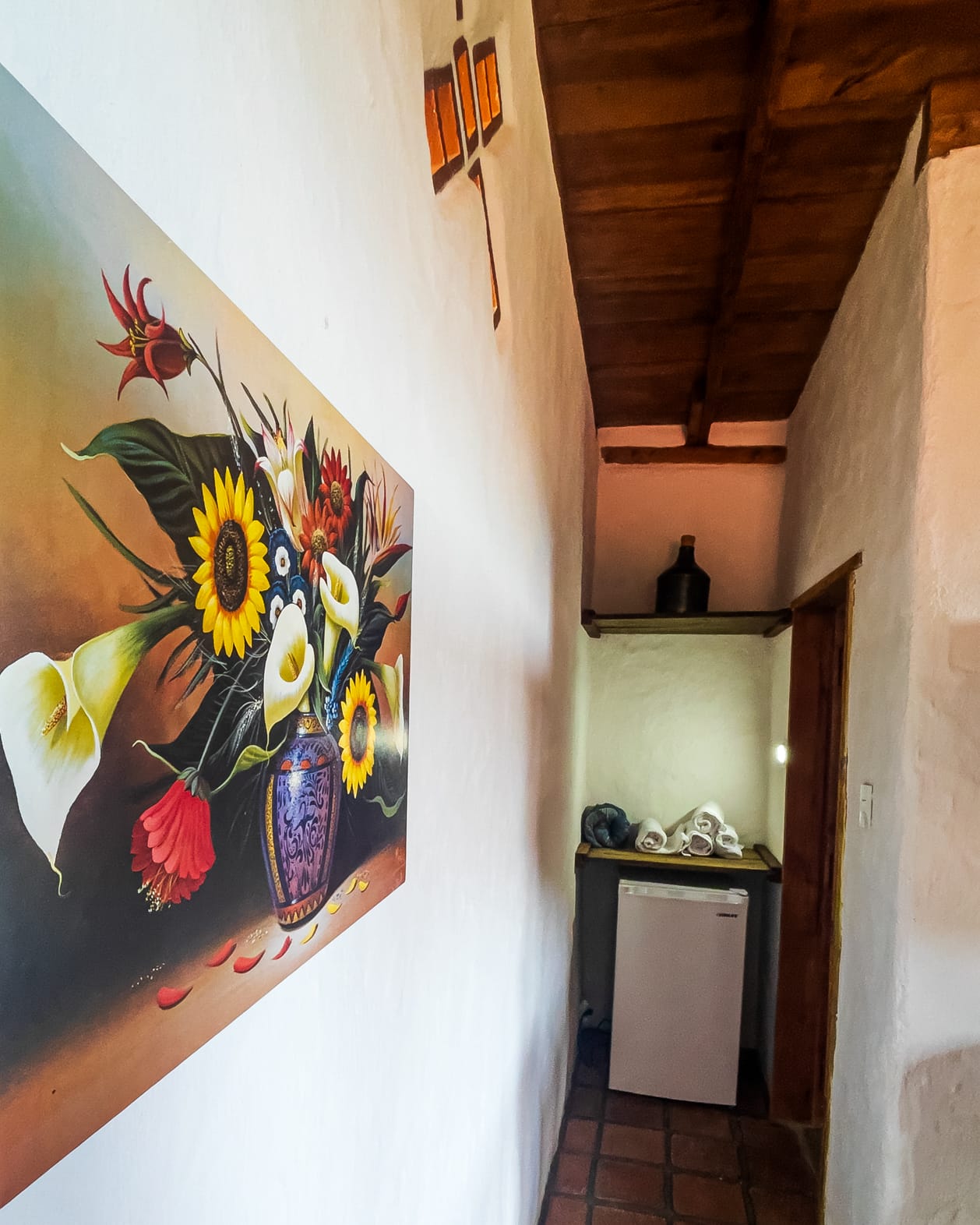 Pasillo con un cuadro grande de girasoles y calas bajo la luz ámbar de los vitrales