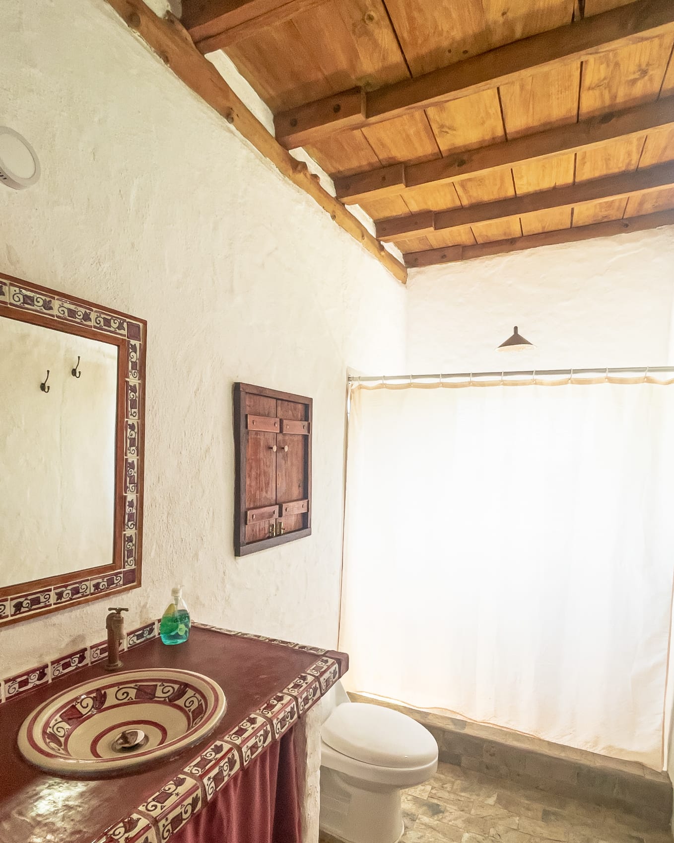 Baño de lavamanos de cerámica pintada a mano, espejo de marco artesanal y cortina de ducha clara