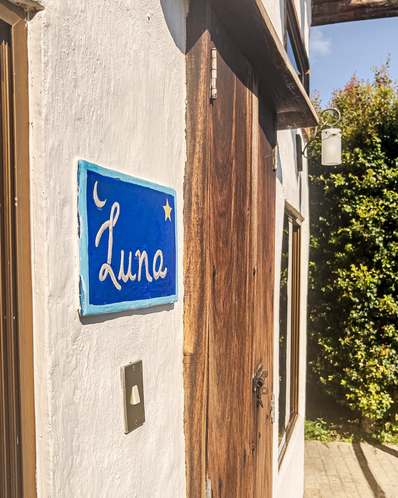 Placa de cerámica azul con el nombre Luna, una lunita y una estrella junto a la puerta de madera