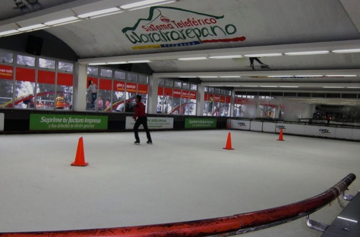 Pista de hielo cubierta del Hotel Humboldt, con un patinador y conos naranjas bajo el letrero del Teleférico Warairarepano