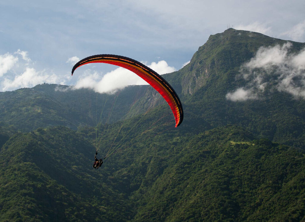 Persona volando en parapente sobre Galipán con vista al mar y la montaña